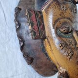 A large Senufo mask made of colored wood, decorated with an anthropomorphic figure