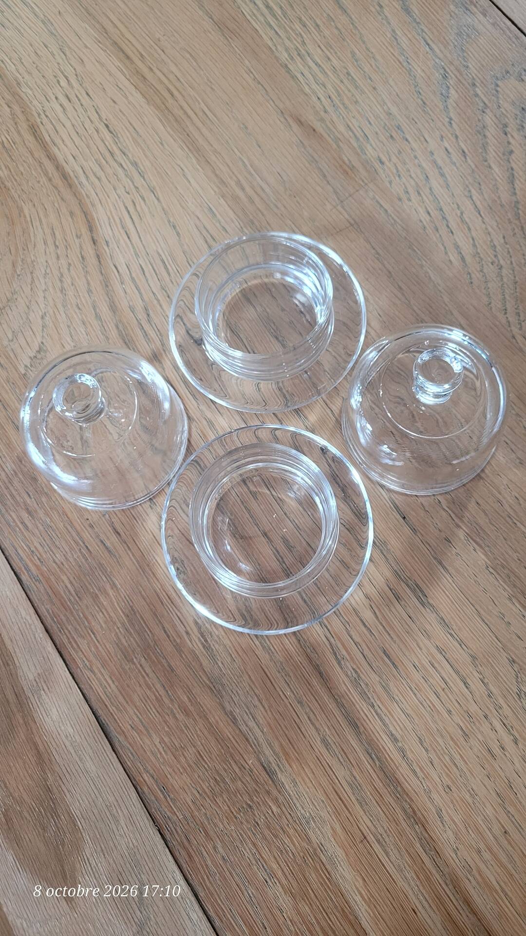 2 transparent glass butter dishes accompanied by their matching cloches.
