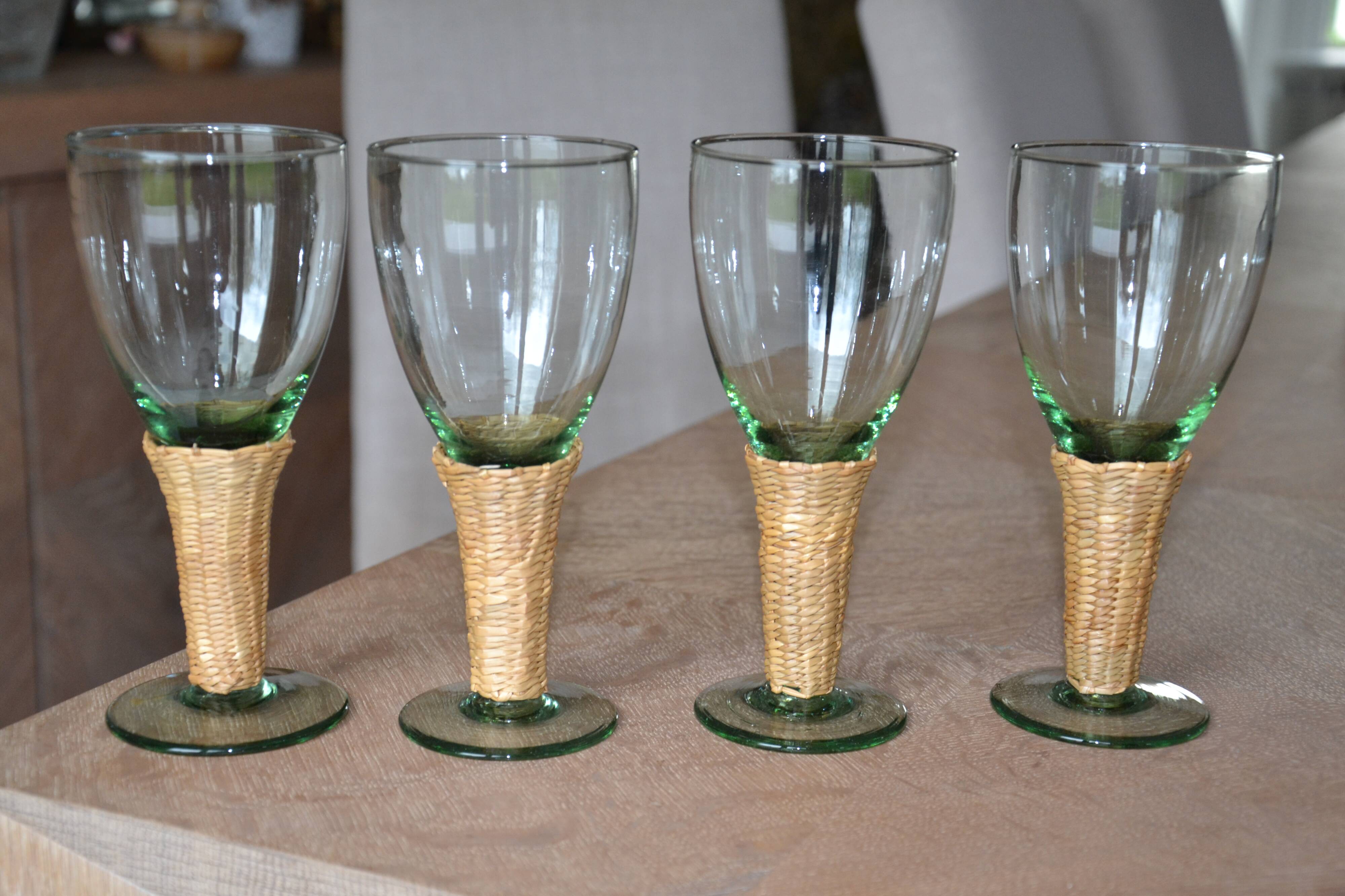 Four stemmed glasses surrounded by rattan.