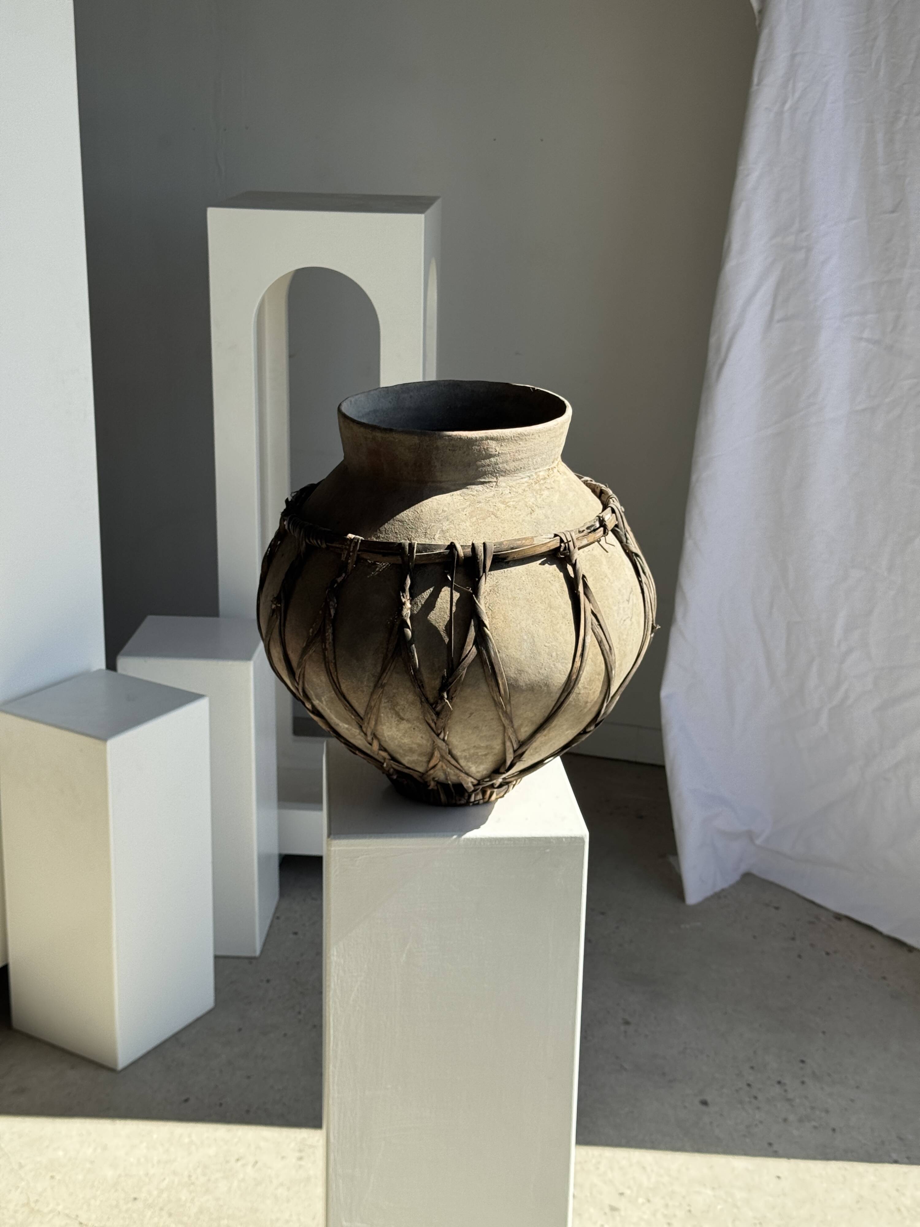 Very large light grey terracotta pot with handles and rattan crossbars.