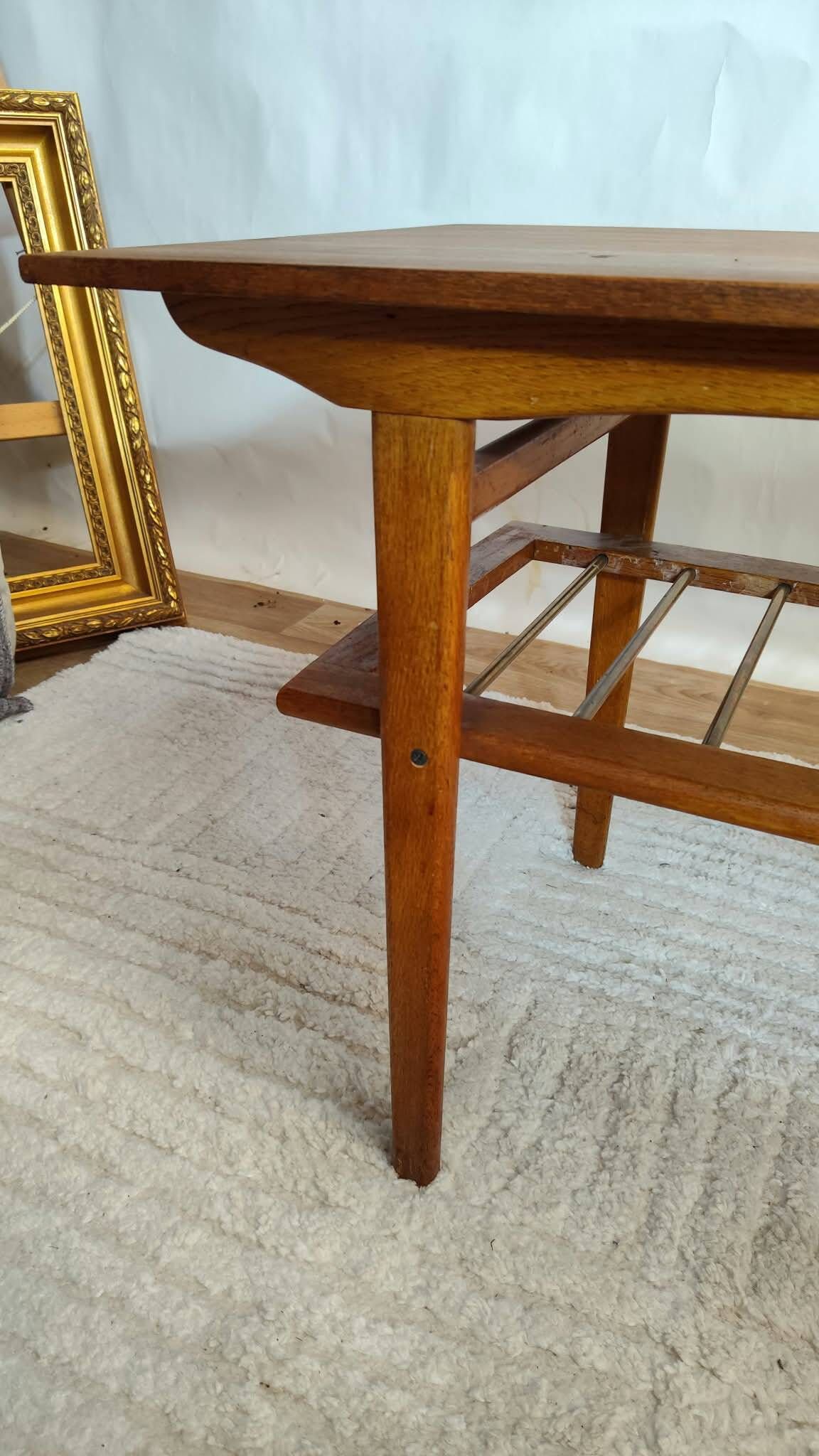 Scandinavian coffee table in teak with a lower shelf and brass bars.