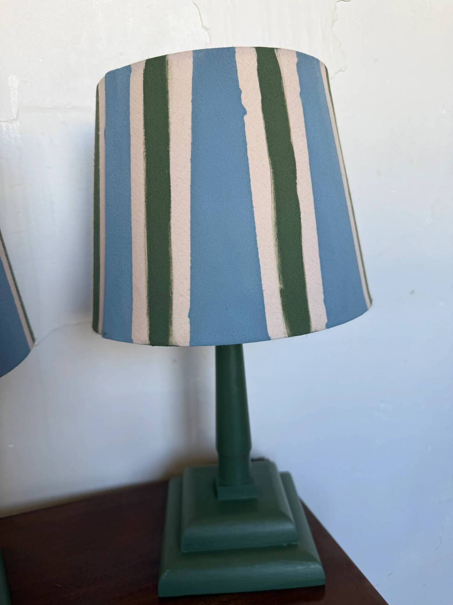 Pair of vintage wooden lamps with their striped beige, blue, and green shades.