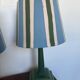 Pair of vintage wooden lamps with their striped beige, blue, and green shades.