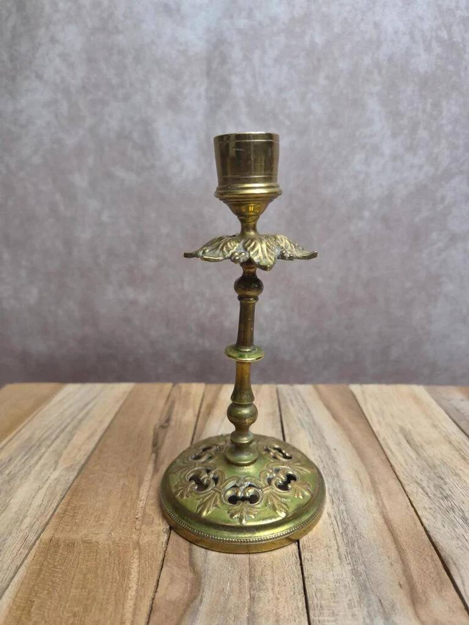 Antique brass candlestick with patina, openwork vintage foliage decoration.