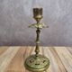 Antique brass candlestick with patina, openwork vintage foliage decoration.