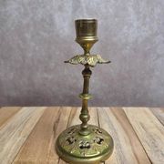 Antique brass candlestick with patina, openwork vintage foliage decoration.