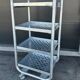 Four-wheeled dessert trolley with 4 perforated metal shelves.