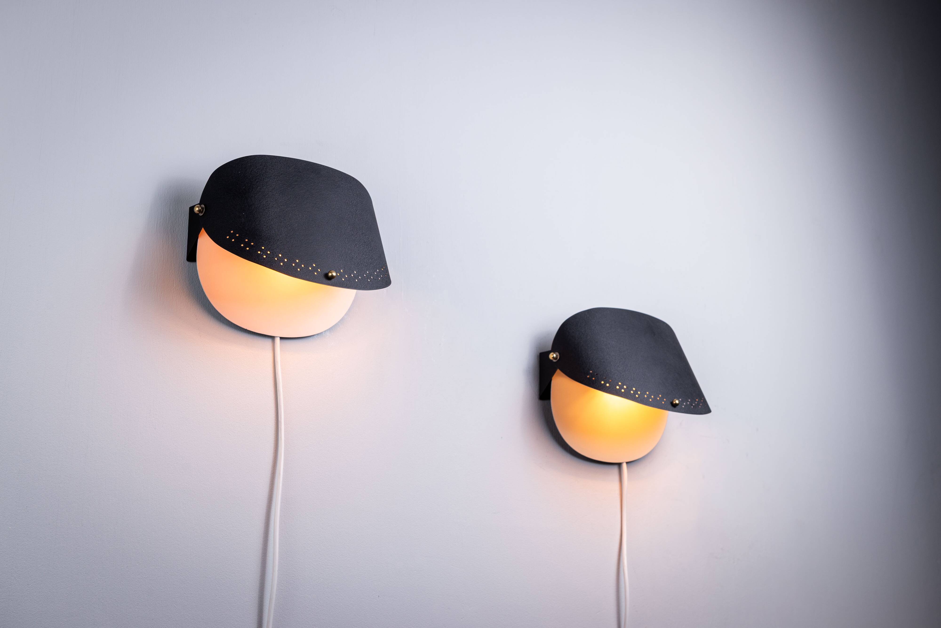Matte black wall lamps with perforated shades and brass details