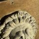 Off-white plaster lion head relief on natural wood panel — Walter De Buck, classical decorative sculpture