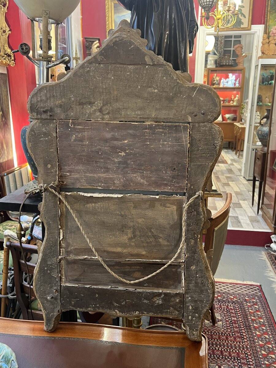 Mirror with carved and gilded wooden frame, 18th century, with scrollwork decoration.