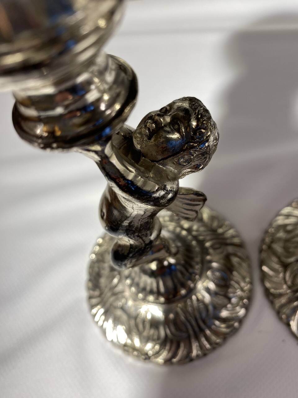 Two silver-plated metal candlesticks decorated with cherubs, 20th century