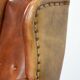 Large sheepskin wingback chair with black piping and decorative nails