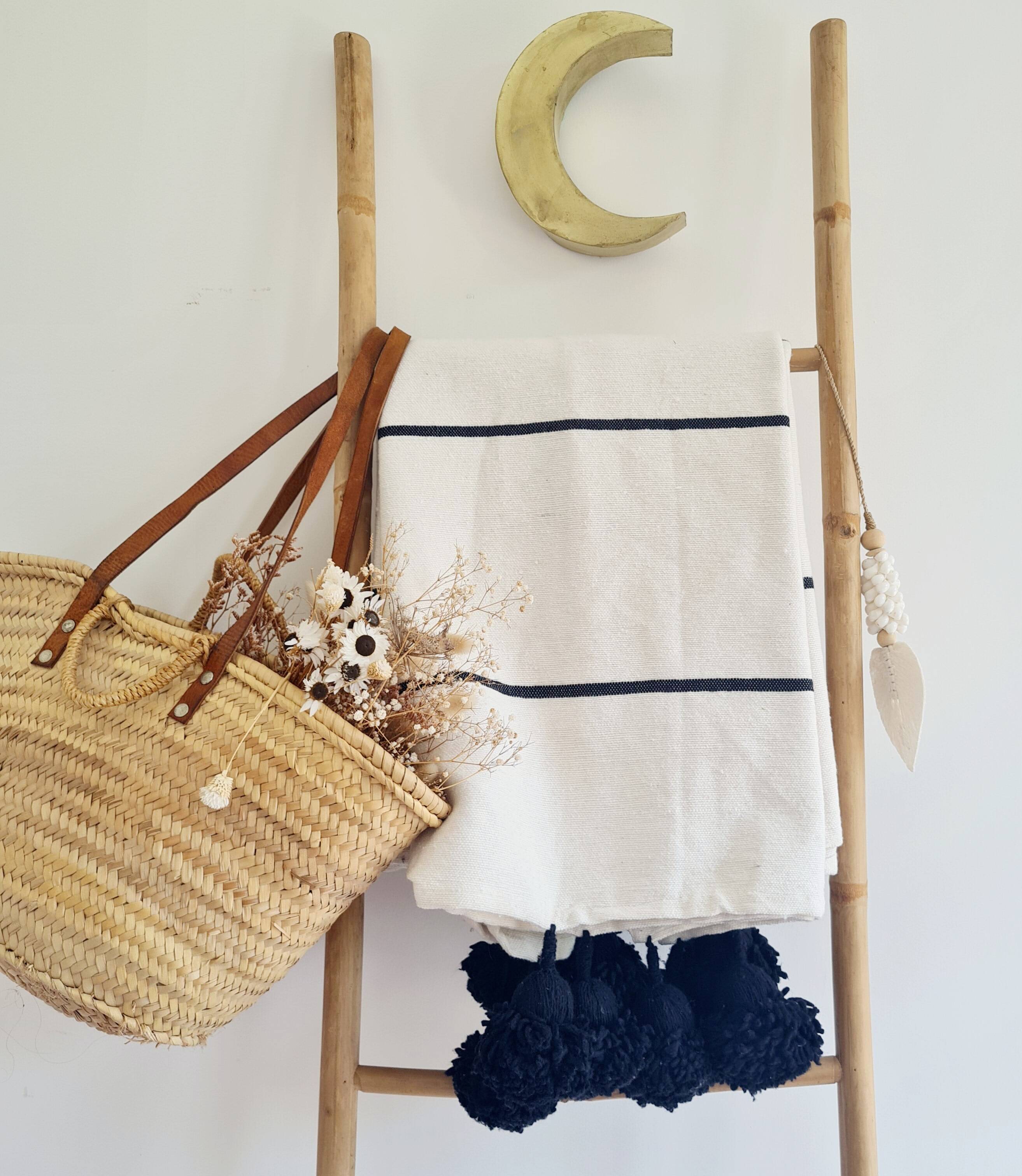Handwoven throw with black stripes and pom-poms