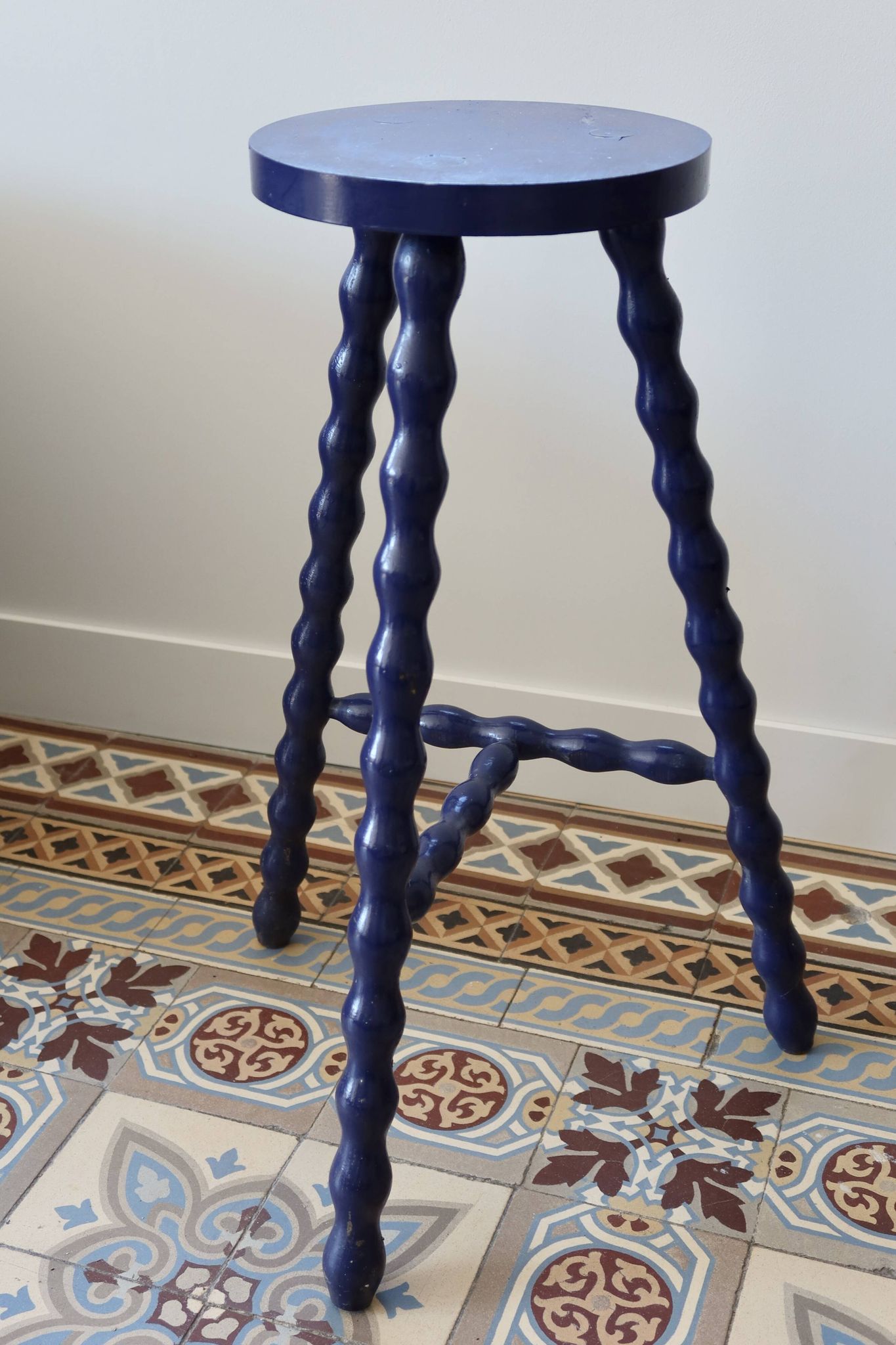 Vintage tripod stool made of turned wood, painted blue.