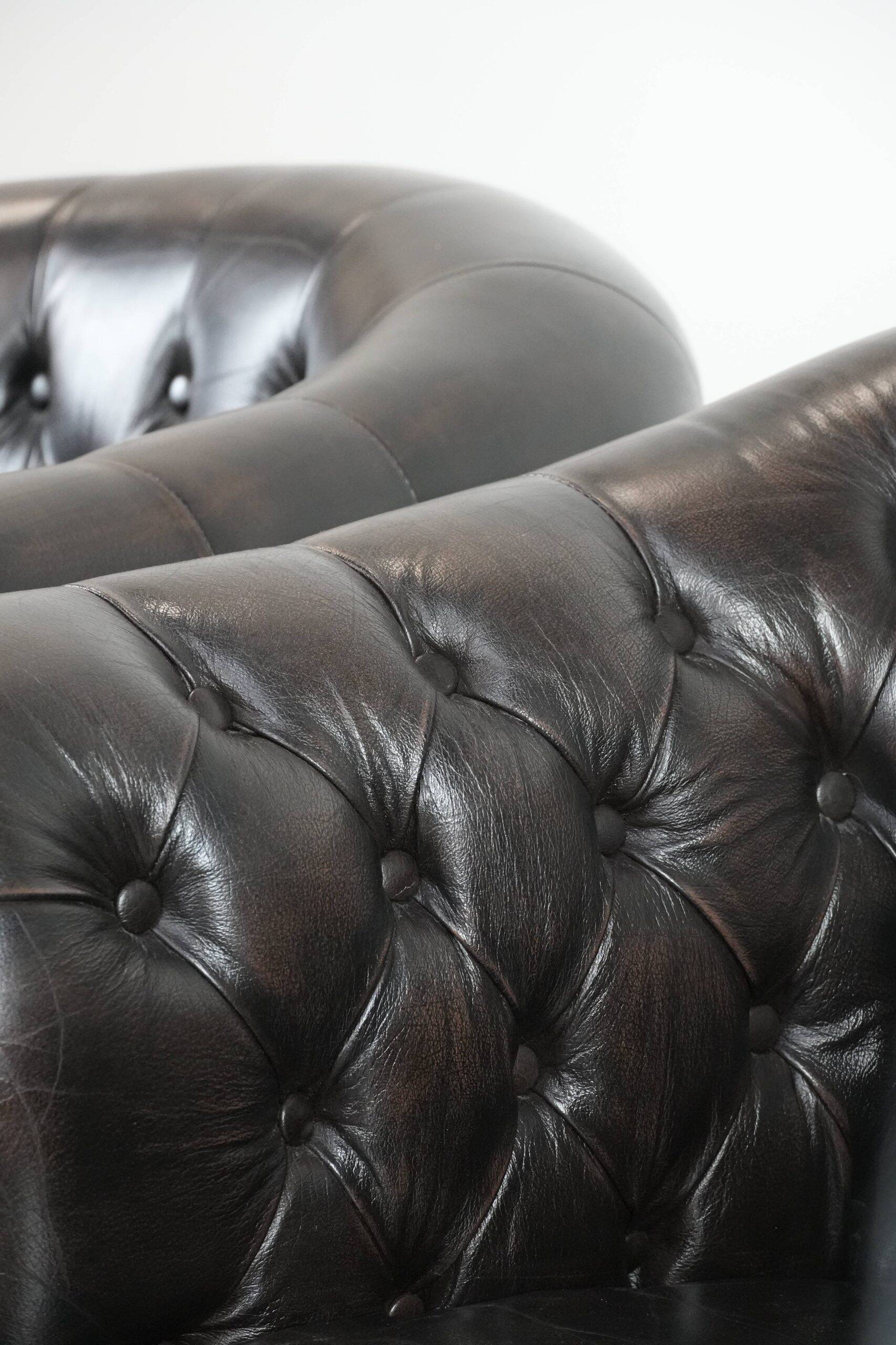 Ensemble de deux luxueux fauteuils club Chesterfield en cuir de vachette noir.