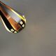 A teardrop-shaped pendant lamp made of copper, black metal, and prisms.