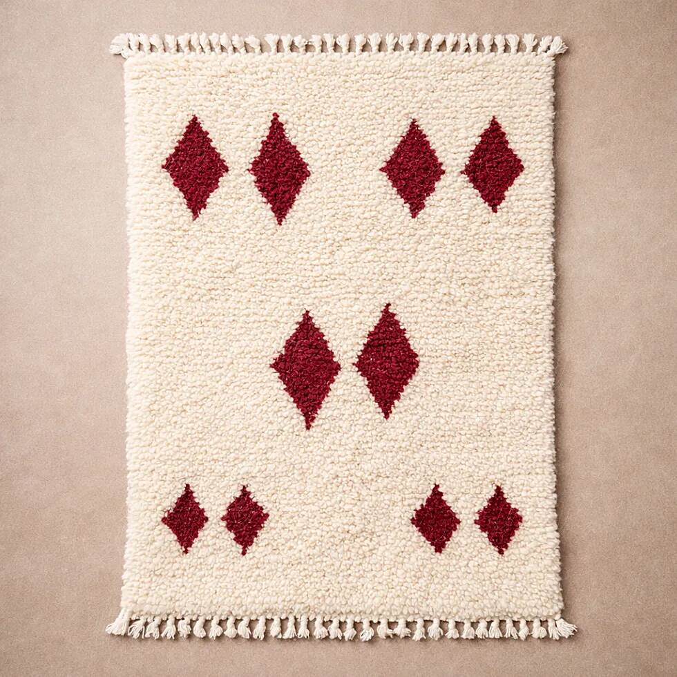 Minimalist cream Berber rug with red diamonds.