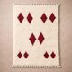 Minimalist cream Berber rug with red diamonds.