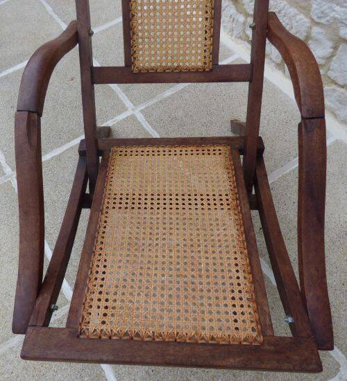 Antique folding chair with caned seat and backrest made of wood.