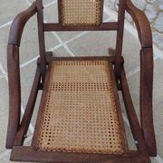 Antique folding chair with caned seat and backrest made of wood.