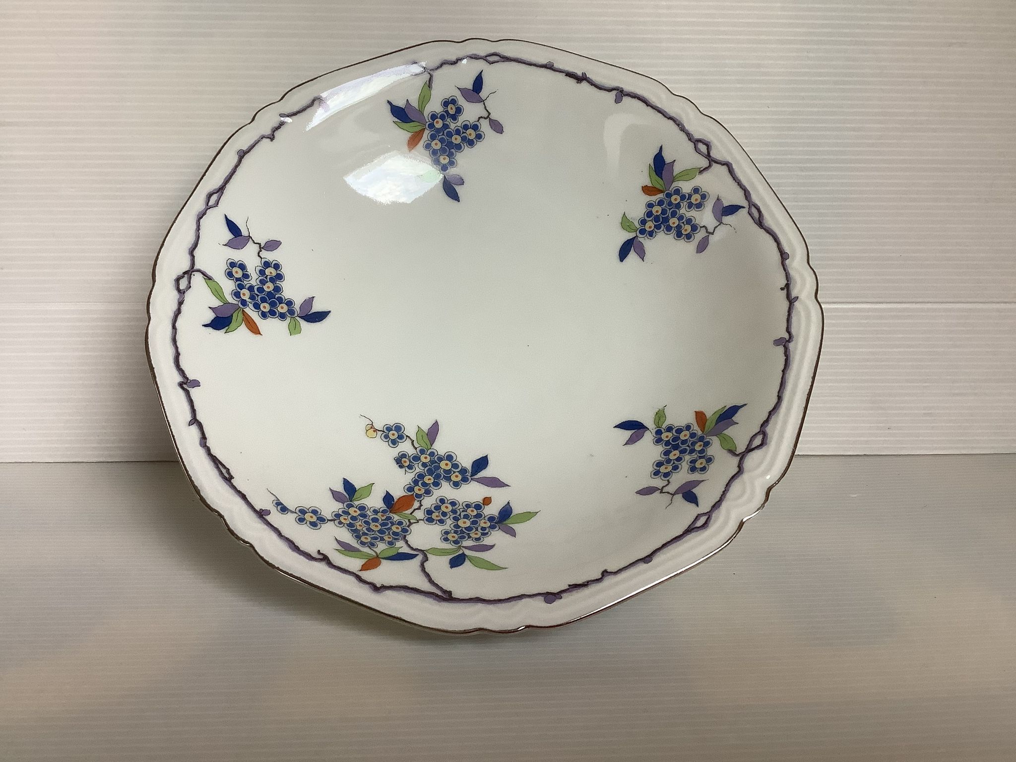 Old shower tray with silver trim and forget-me-not flowers.