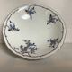 Old shower tray with silver trim and forget-me-not flowers.