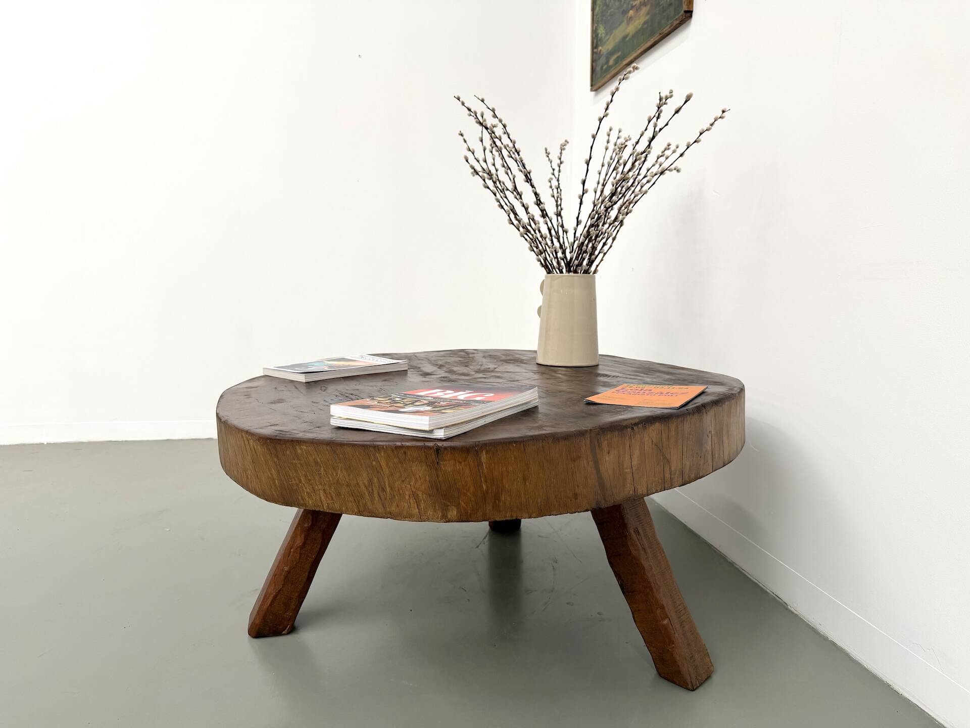 Brutalist coffee table in solid teak, monolithic slab, tripod base.