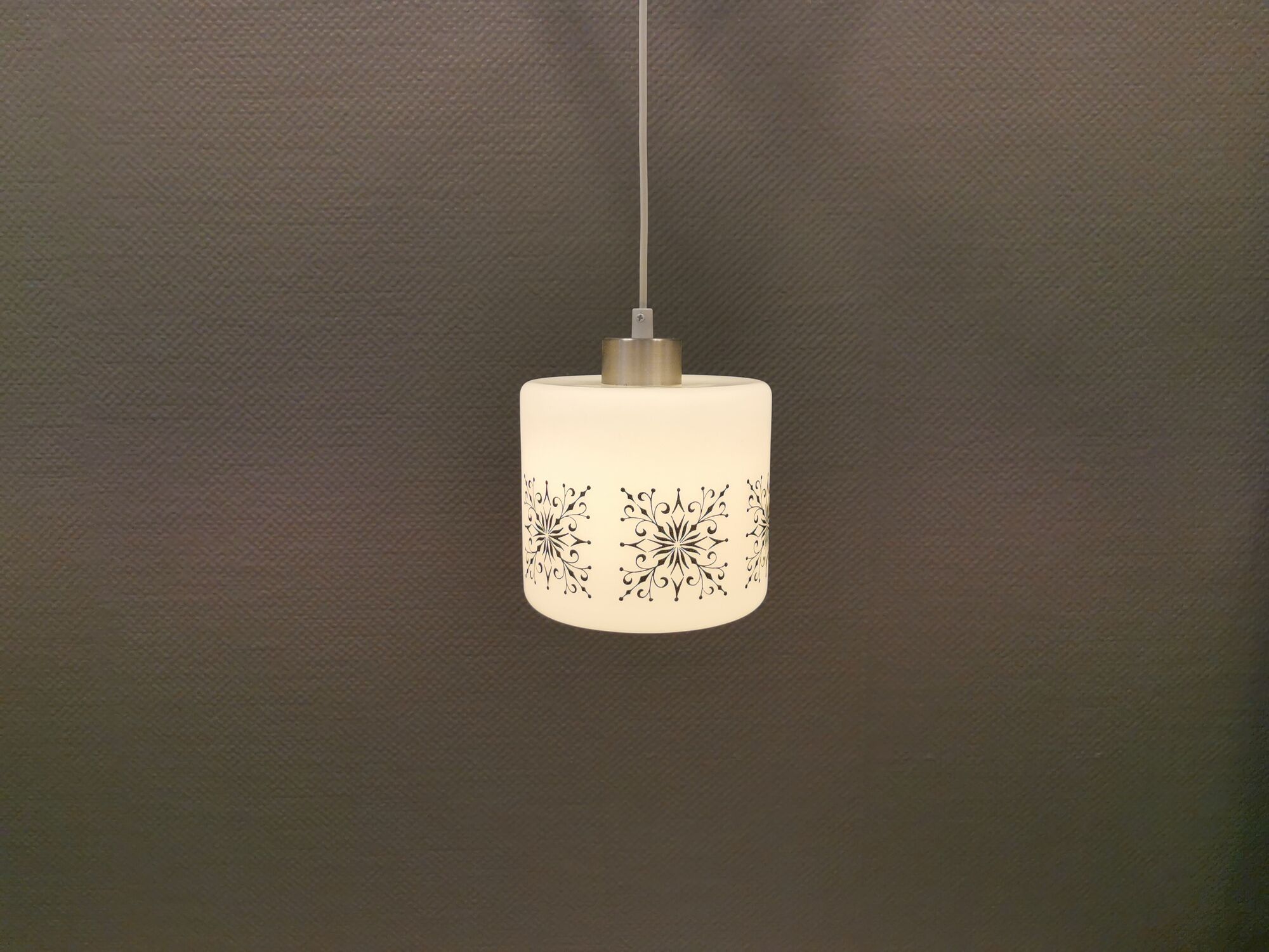 Scandinavian hanging lamp in white glass with inlayed black motifs.