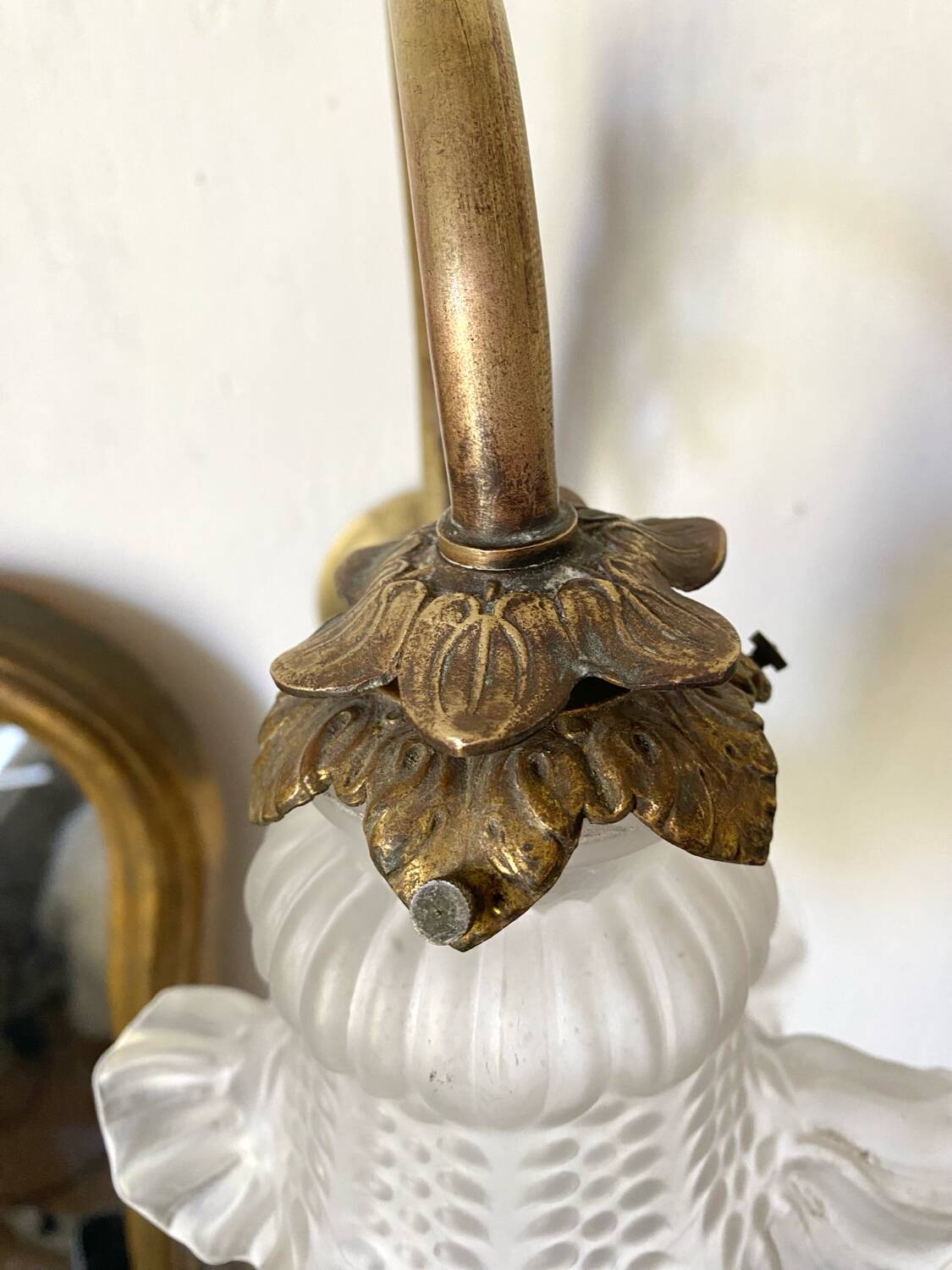 Antique brass wall light with glass shade.