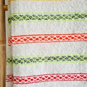 Moroccan plaid made of handwoven wool, decorated with stripes and pom poms.