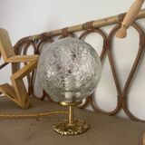 Small handcrafted globe lamp with a cracked finish and a golden brass base.