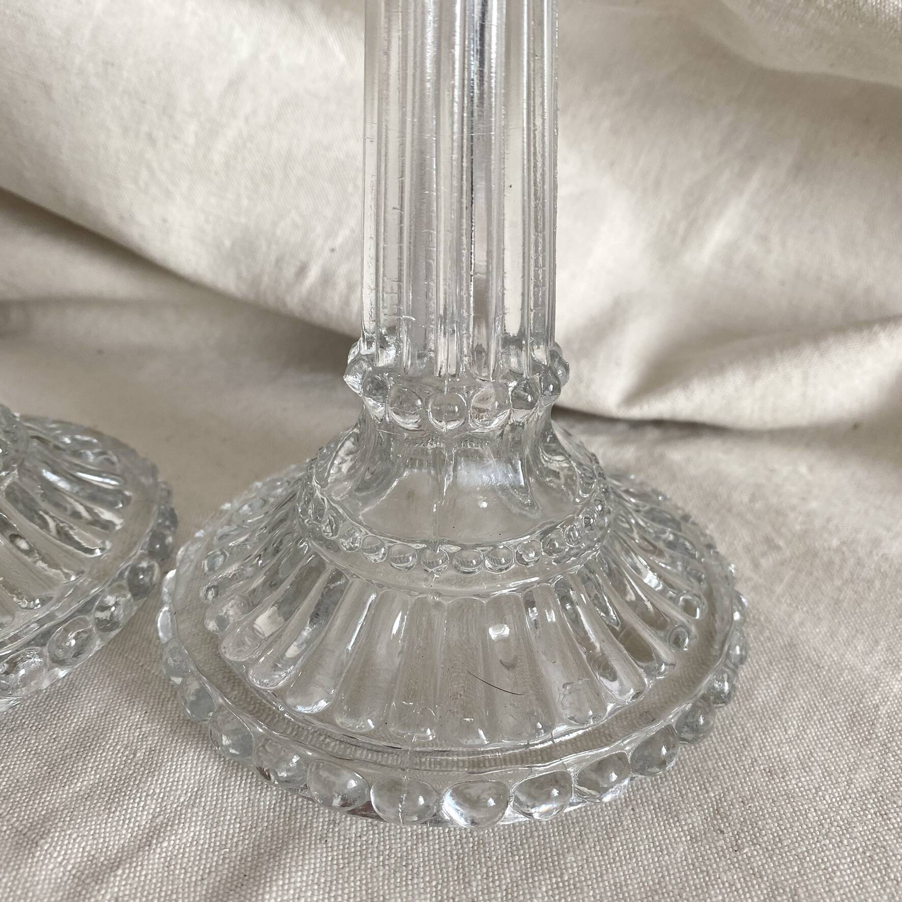 Column candle holders in moulded glass made in France.