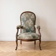 Antique Voltaire armchair in wood and green fabric with floral patterns.