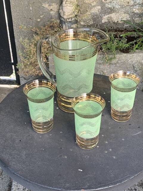 Serve an orangeade, a carafe and 3 glasses in green granite with golden trim.