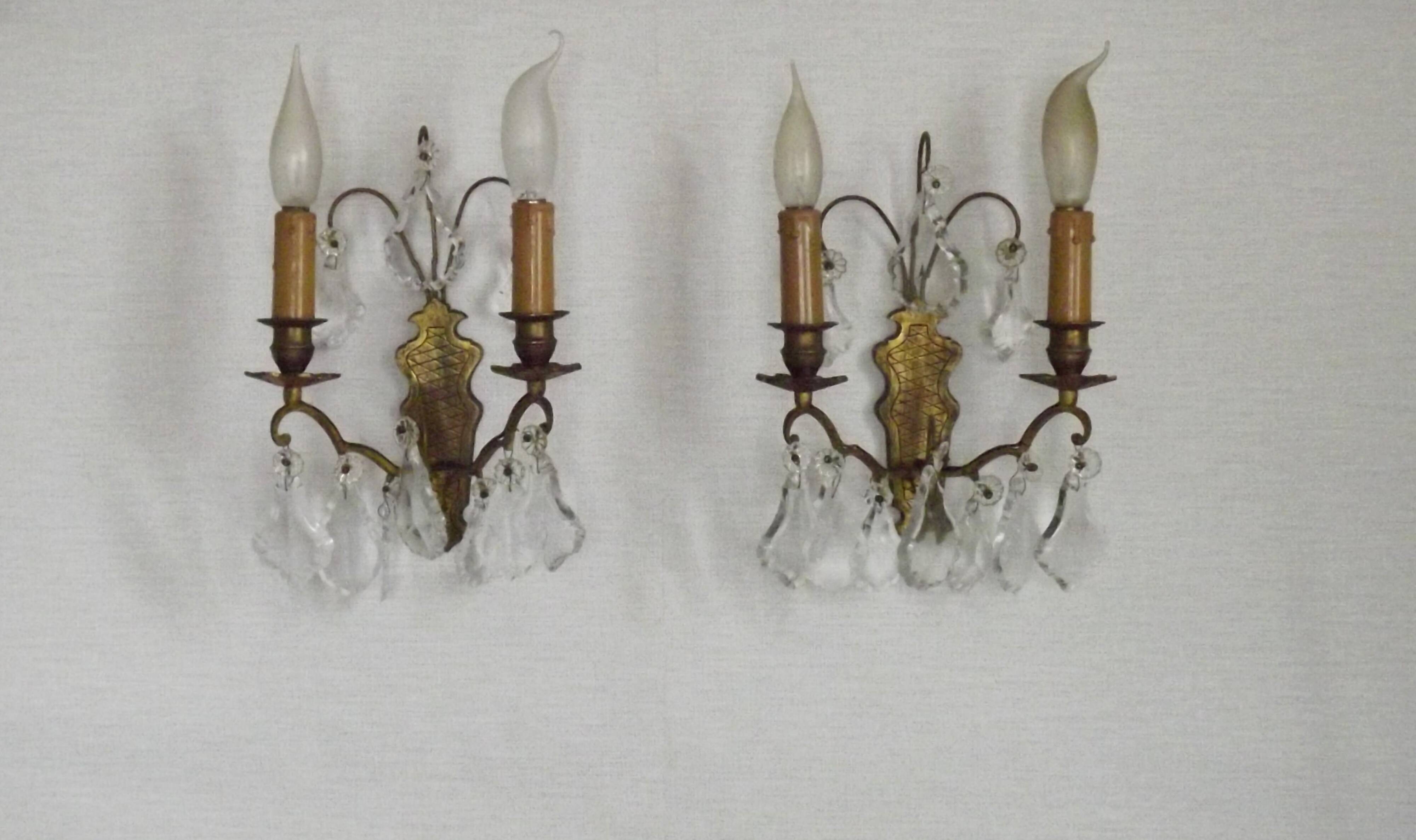 Pair of French antique brass double wall lights with assorted crystals.