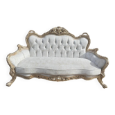 A white and gold tufted beech wood sofa in Louis XV style.