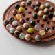 Vintage 1960s solitaire game, wooden board with stone marbles.