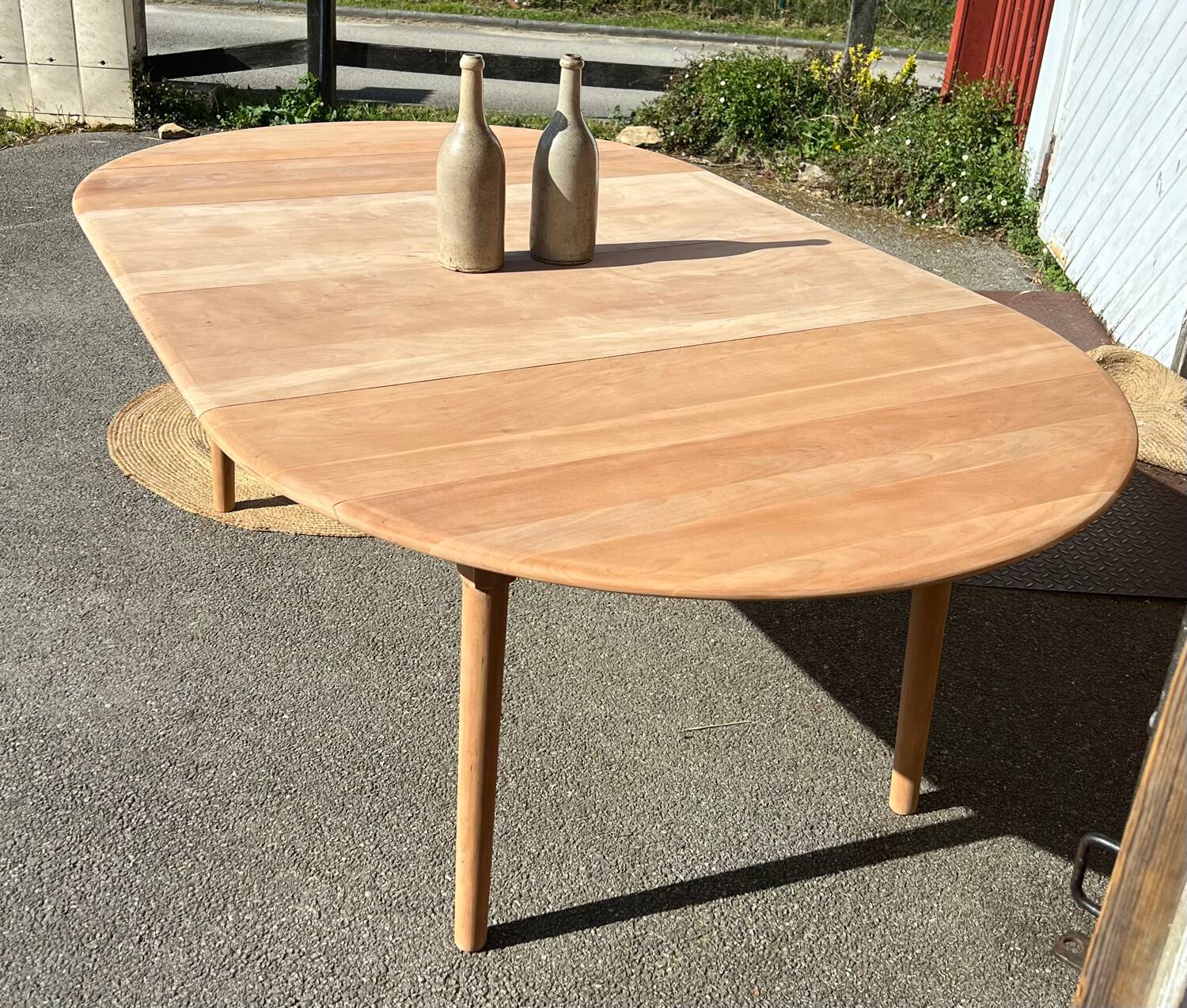 Large round family table with 2 extensions in solid raw wood.