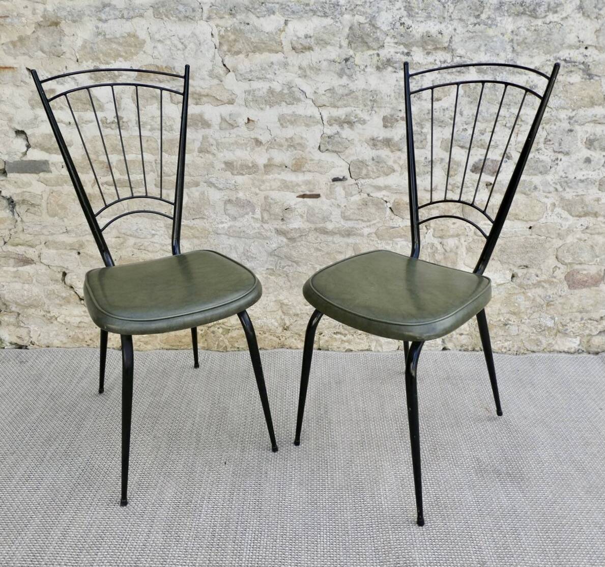 Black metal chairs with khaki faux leather seats, circa 1960.