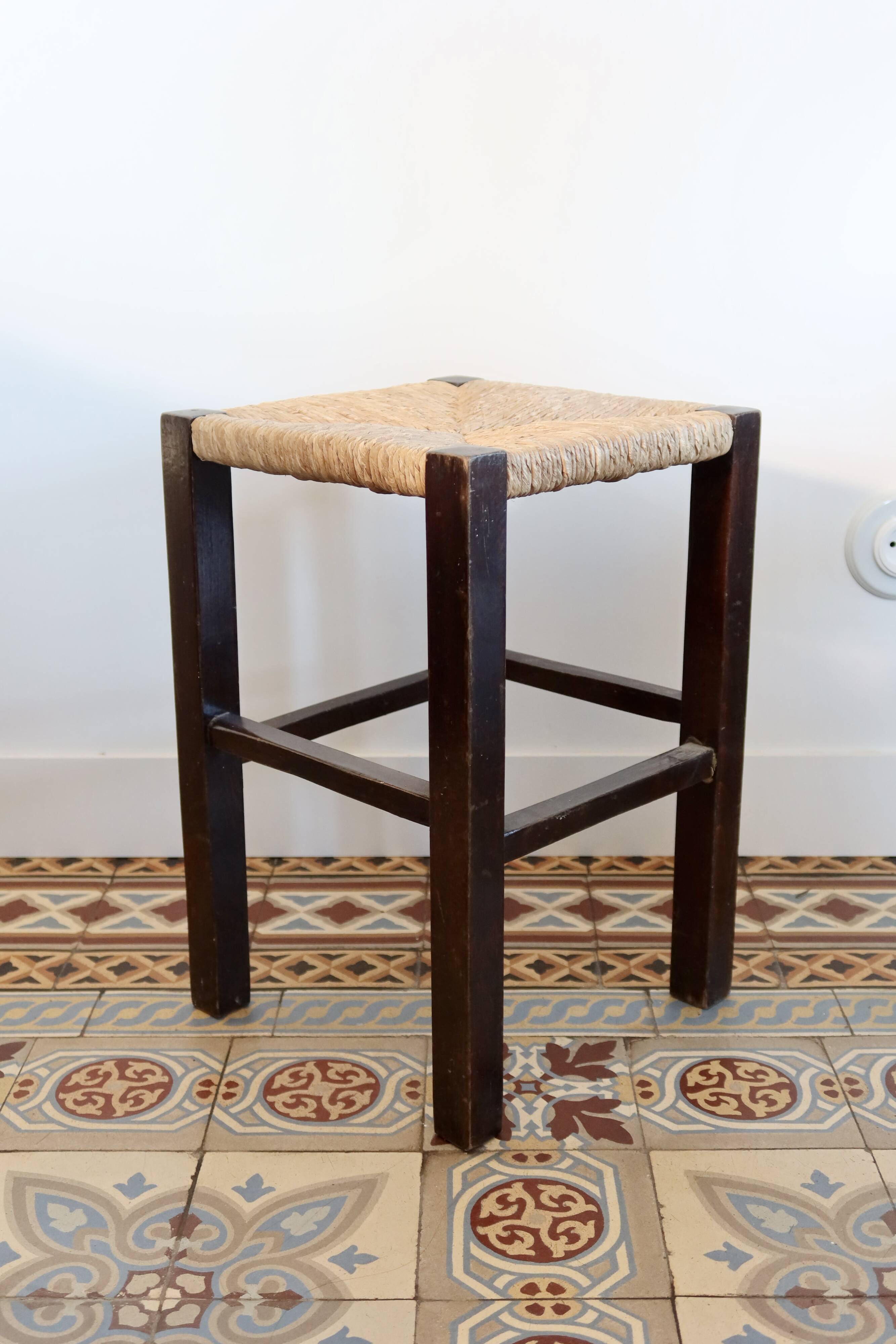 Vintage rustic stool in wood with a straw seat.