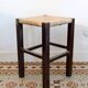 Vintage rustic stool in wood with a straw seat.