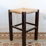 Vintage rustic stool in wood with a straw seat.