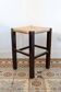 Vintage rustic stool in wood with a straw seat.