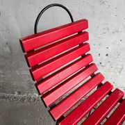 Red slatted chair with a black metal frame.