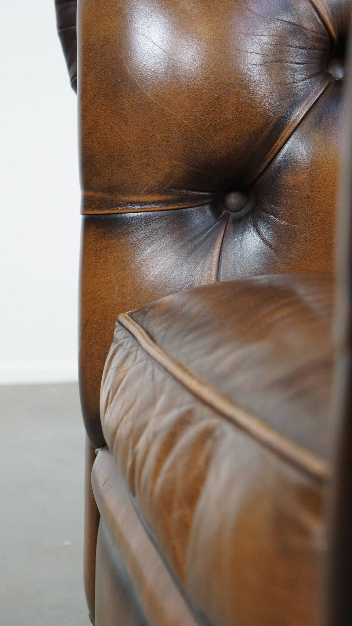 A well-maintained cowhide leather English Chesterfield armchair