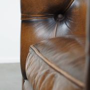 A well-maintained cowhide leather English Chesterfield armchair