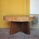 Brutalist wooden coffee table, cruciform leg with a tree trunk top.