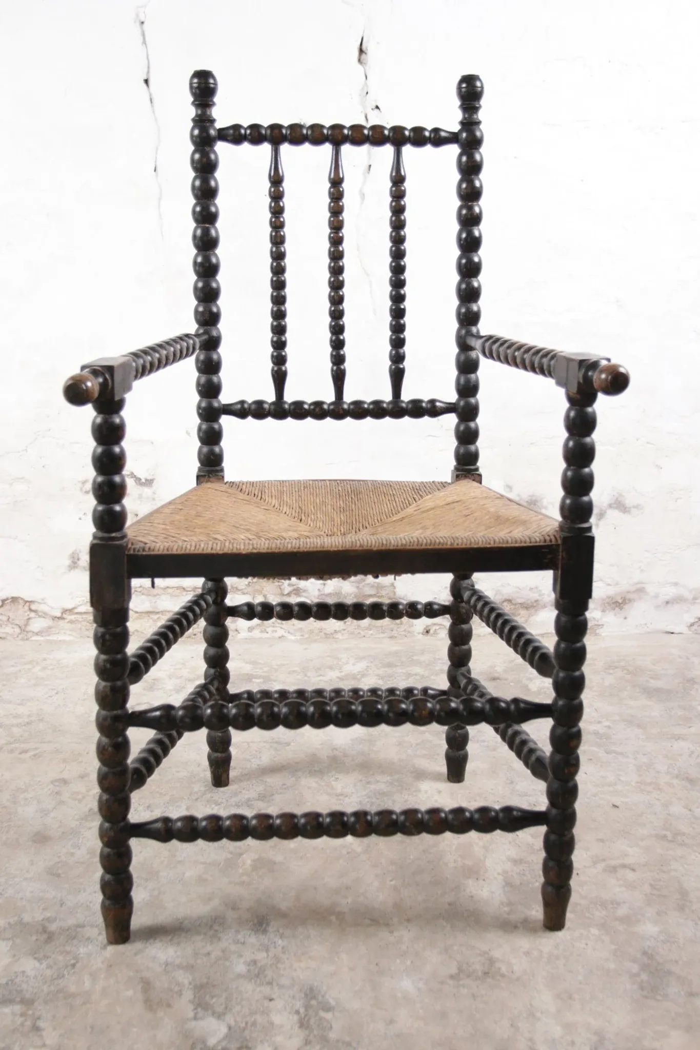 Black bobbin chair with armrests and rush seat – ca. 1900-1930