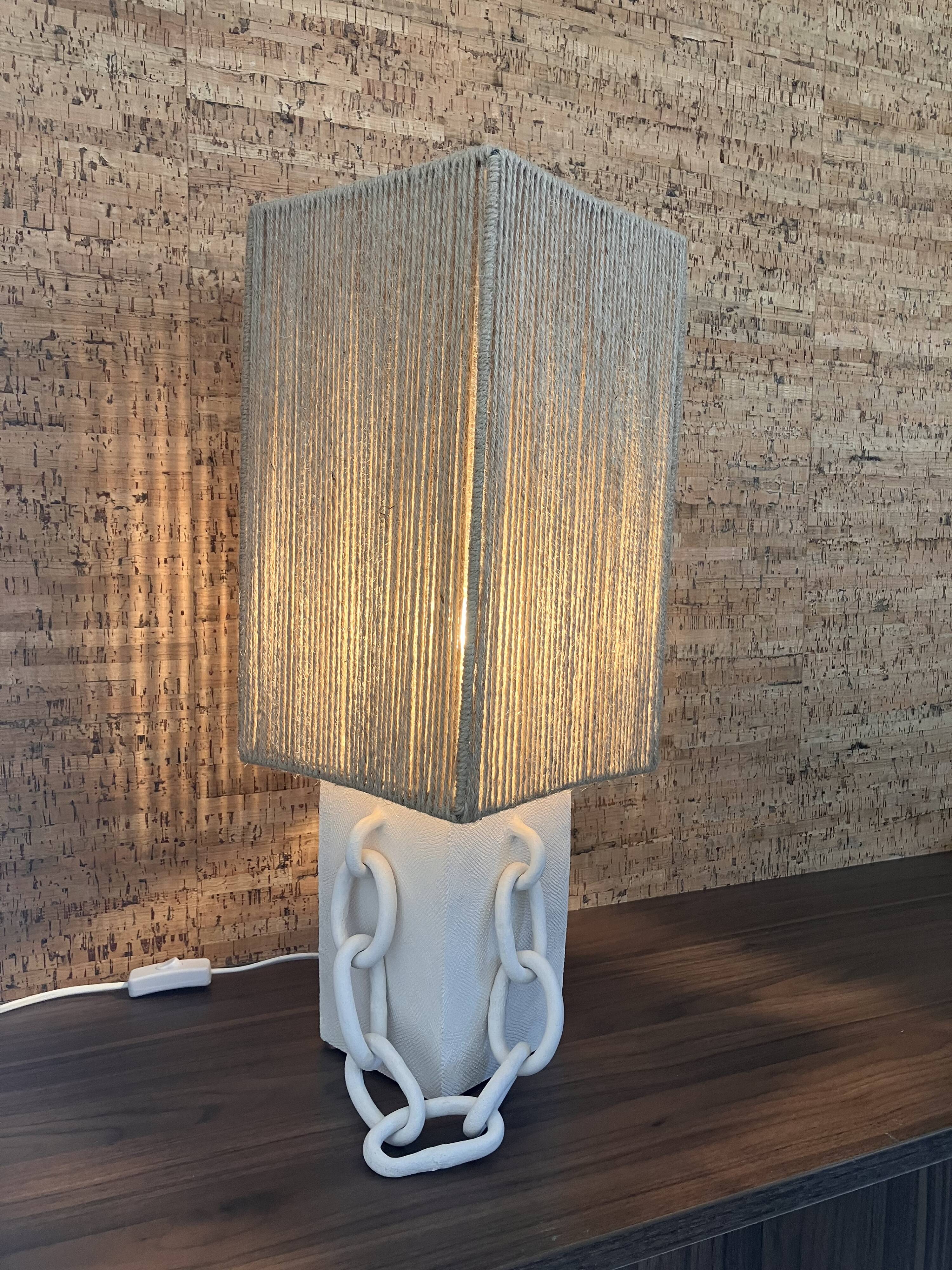 Table lamp in ceramic with decorative chain and cord shade.