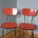 Chairs in red-orange formica and chrome metal.